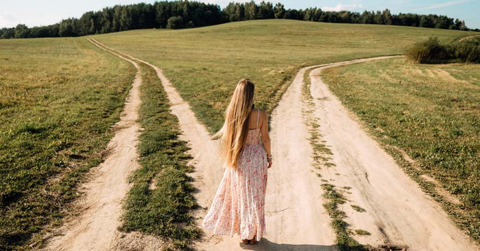 Woman standing at fork in the road in nature